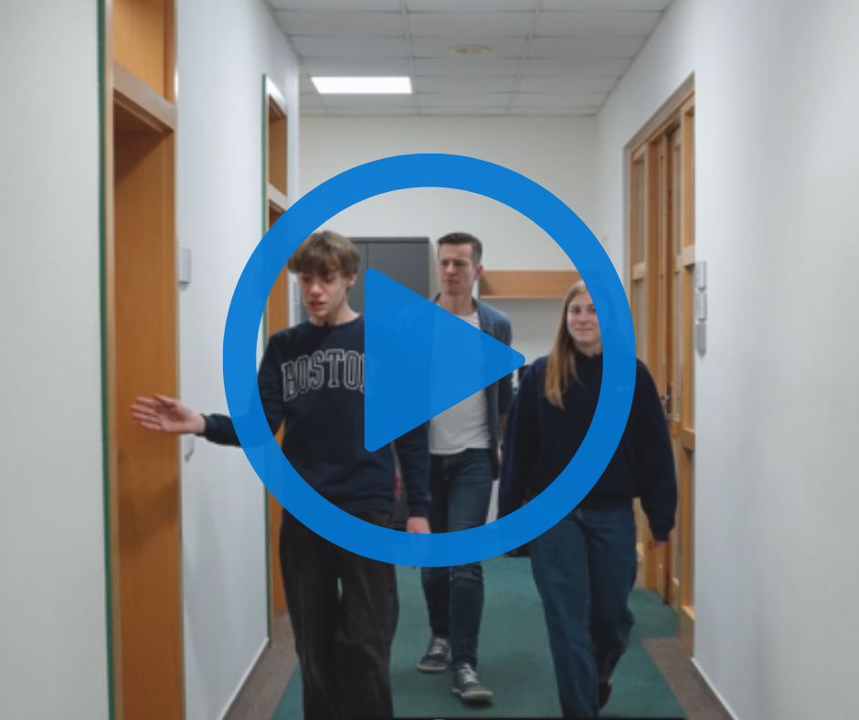 Na obrázku jsou v pozadí děti spolu s Martinem Benešem. Vedou ho chodbou kanceláře. V popředí je tlačítko Play.