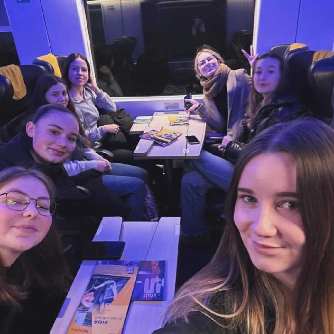 Skupina 7 usmívajících se studentek jedoucí ve vlaku do Brna. 
