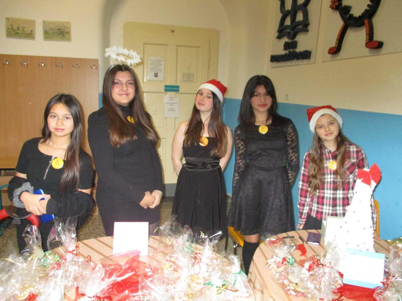 Skupina pěti dívek prodávajících perníčky na vánočním jarmarku.
