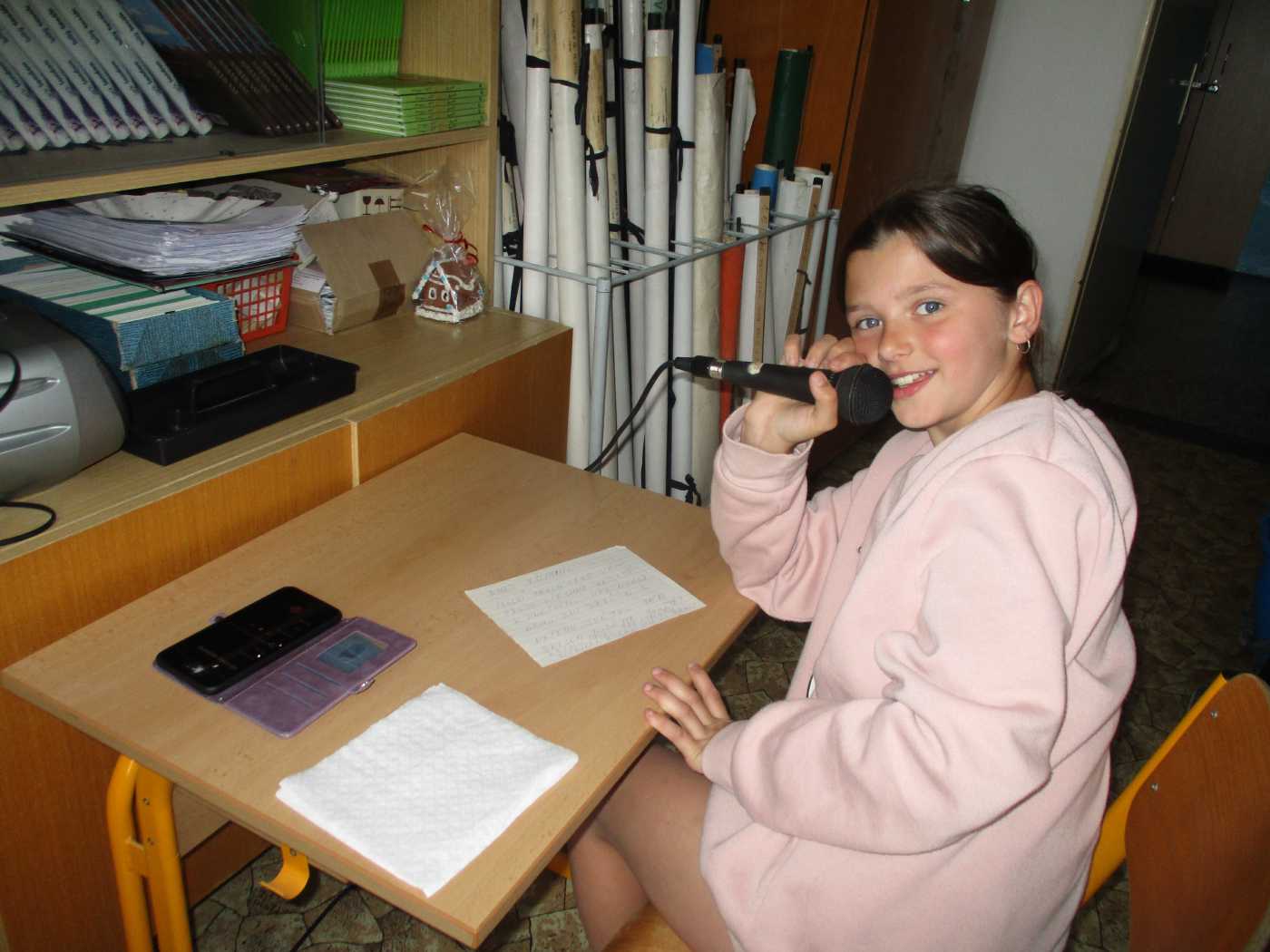 Dívka s mikrofonem pouštějící muziku školním rozhlasem. 